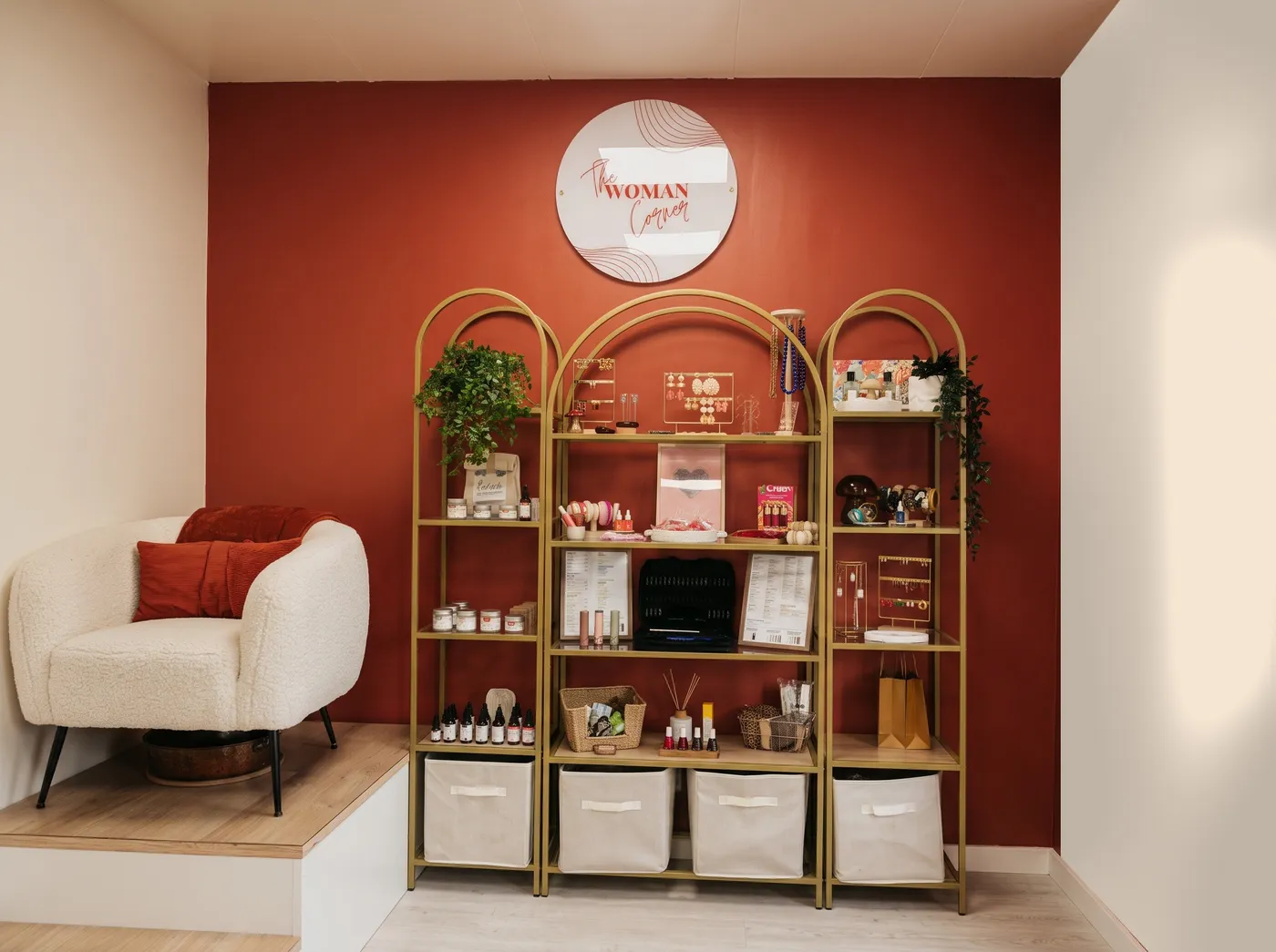 L'institut The Woman Corner : mur terracotta au logo et étagères dorées en arche garnies de produits
