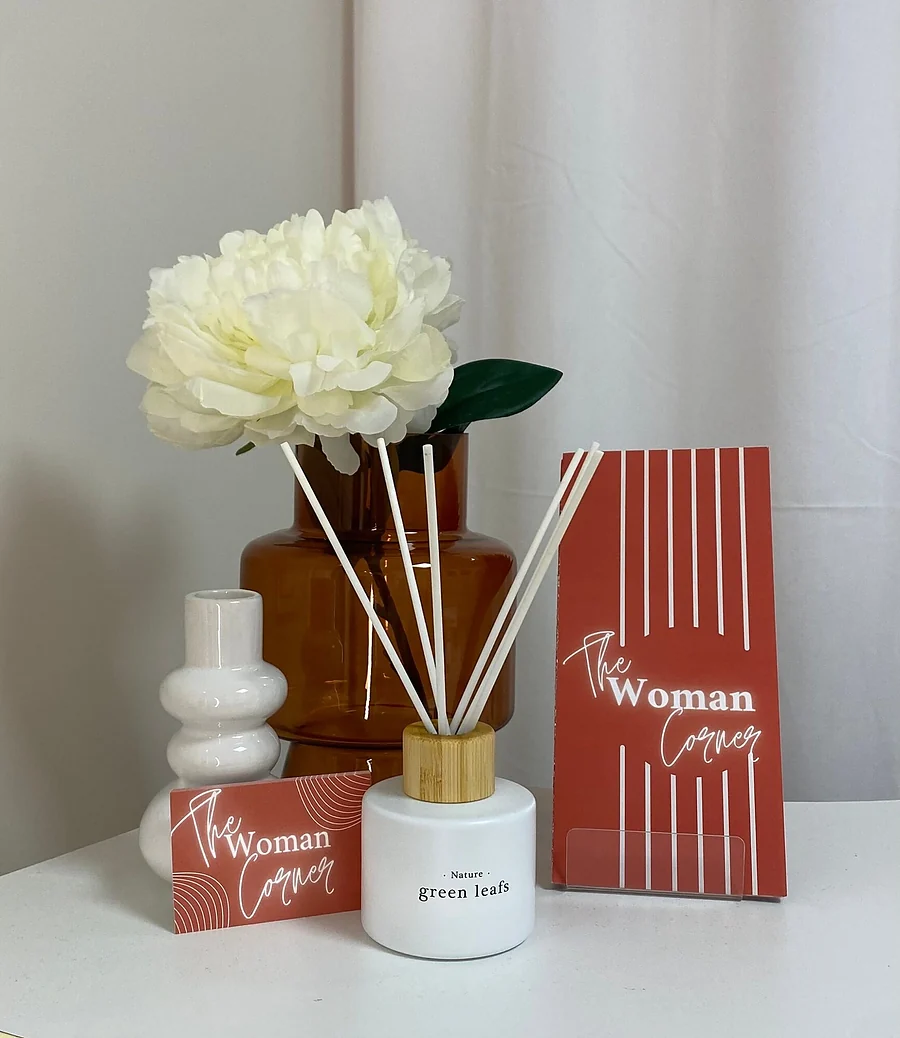Coin accueil de l'institut de beauté : diffuseur de parfum, bouquet de pivoines et cartes The Woman Corner